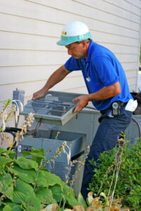 AC repair tech removing the fan grate from the top of an outdoor AC unit.