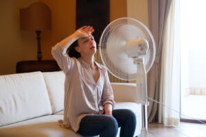 overheated-person-in-front-of-a-fan-wiping-sweat-off-forehead